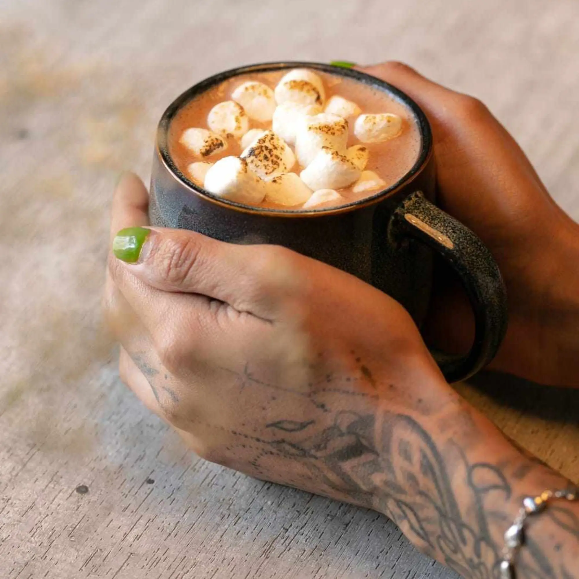 Chocolate caliente con marshmallows entre las manos