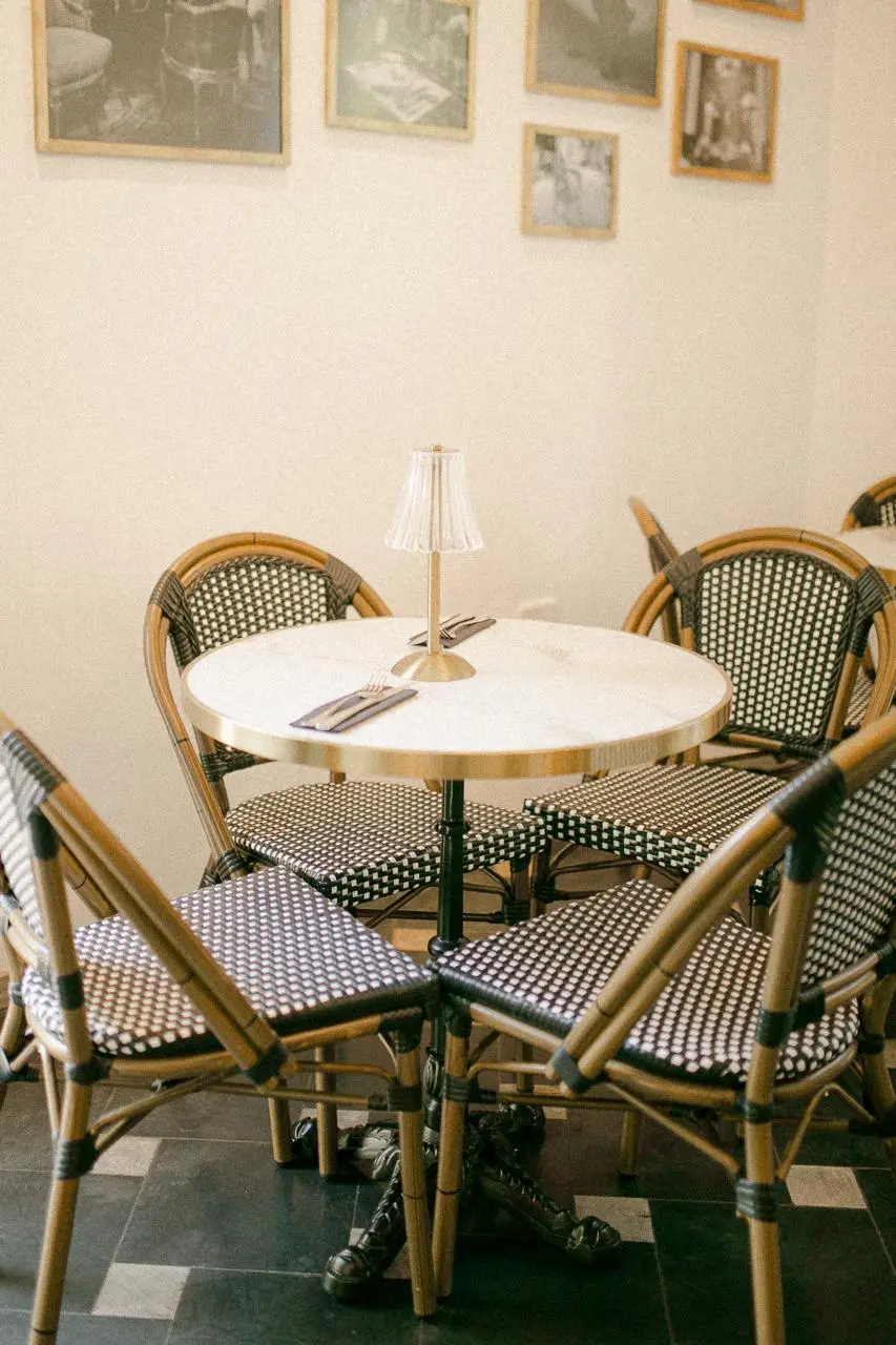 Sillas de bistró y mesa redonda en un salón con cuadros